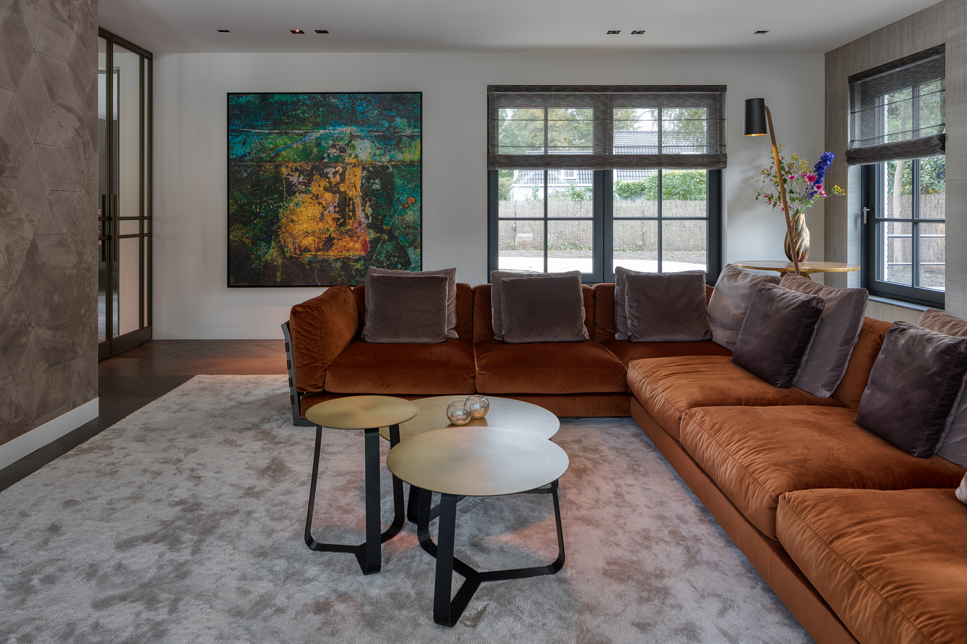 living room with large brown corner sofa on a large soft grey rug, leather and artworks adorn the walls