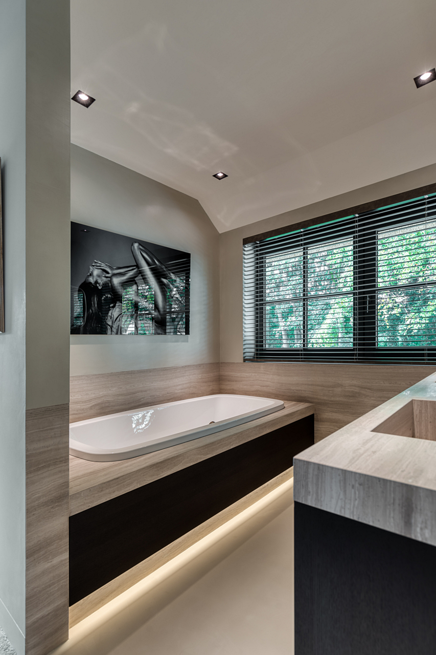 Bathroom with heated cast floor and built-in bathtub overlooking shuttered windows