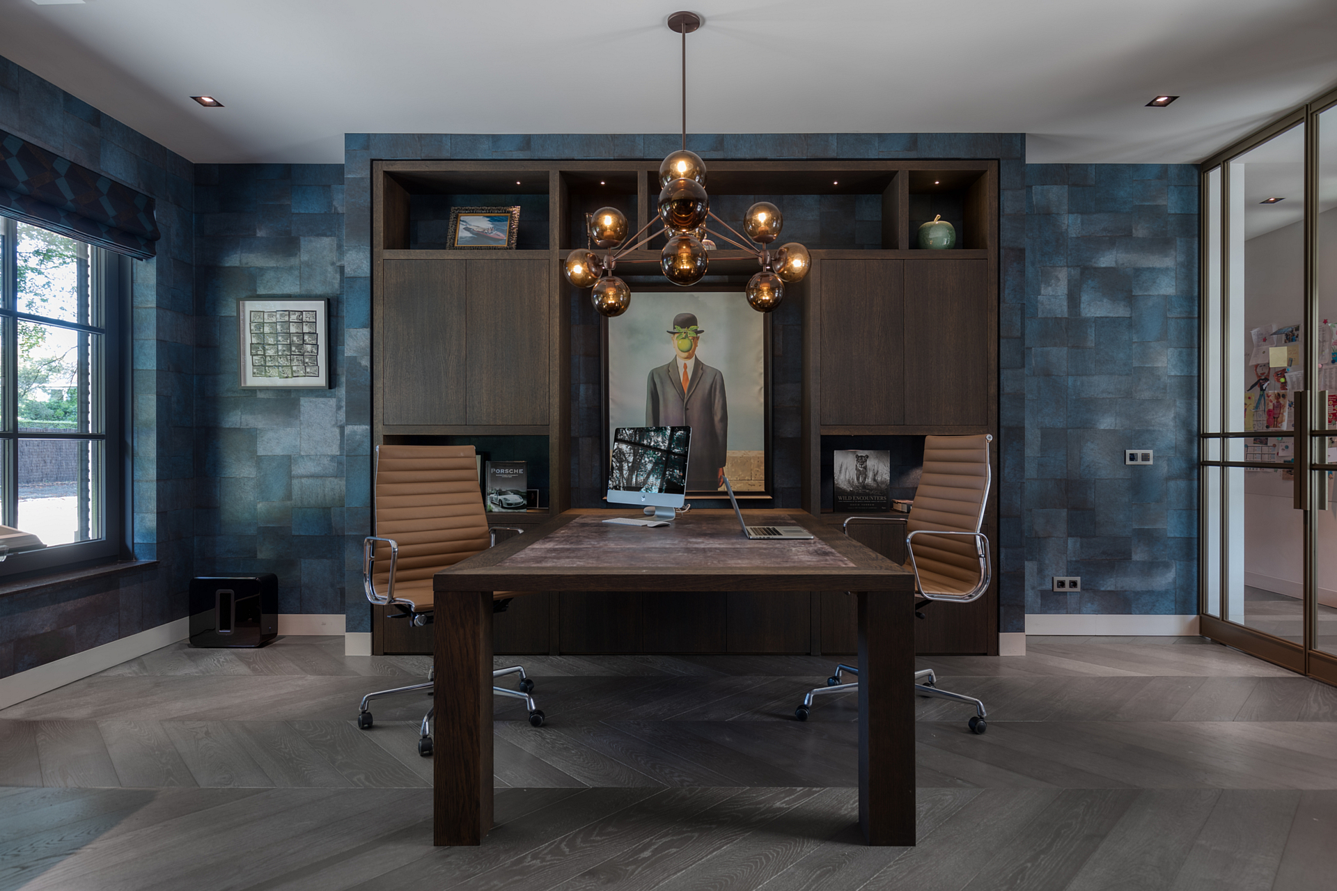 Home office with tantalizing blue wallpaper, a retro fish bulbed chandalier hangs over the desk.